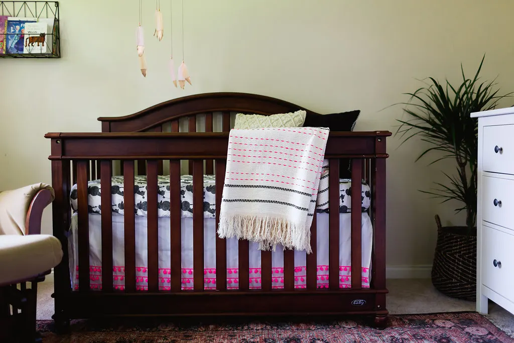 Whimsical Eclectic Nursery with gold dipped feather mobile and pom pom fringed crib skirt