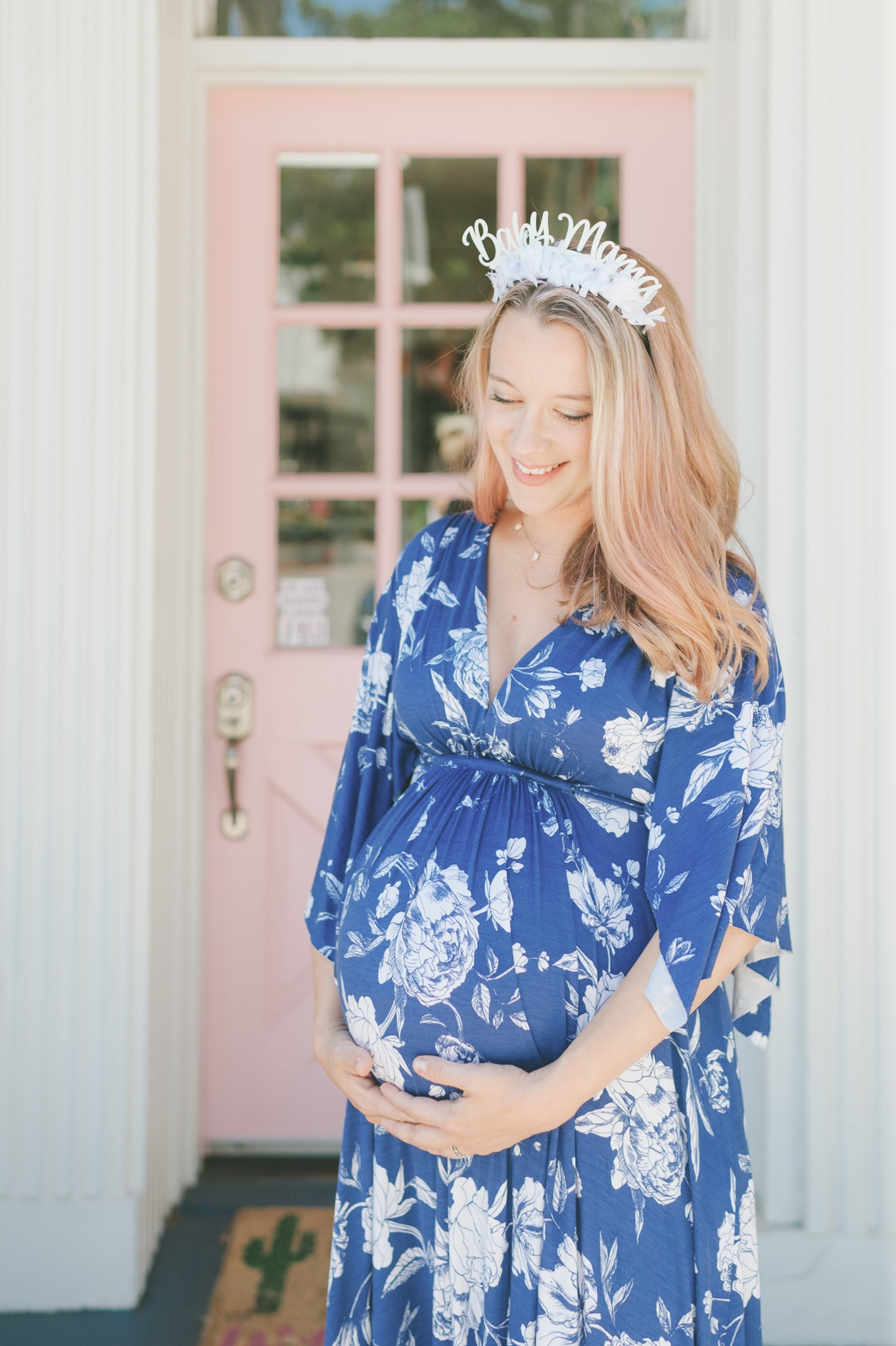 Pregnant Dana Ashmore holding her baby bump with a Baby Mama headband 