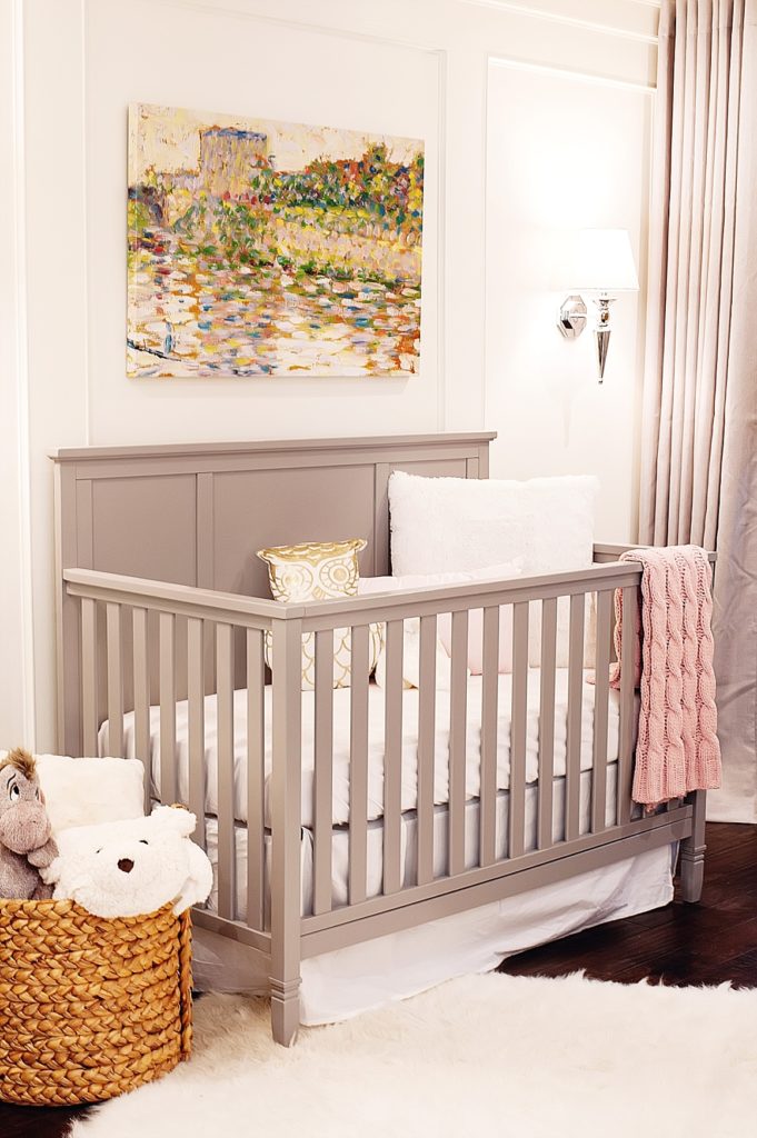 gray crib in a nursery adds some color to white paneled walls