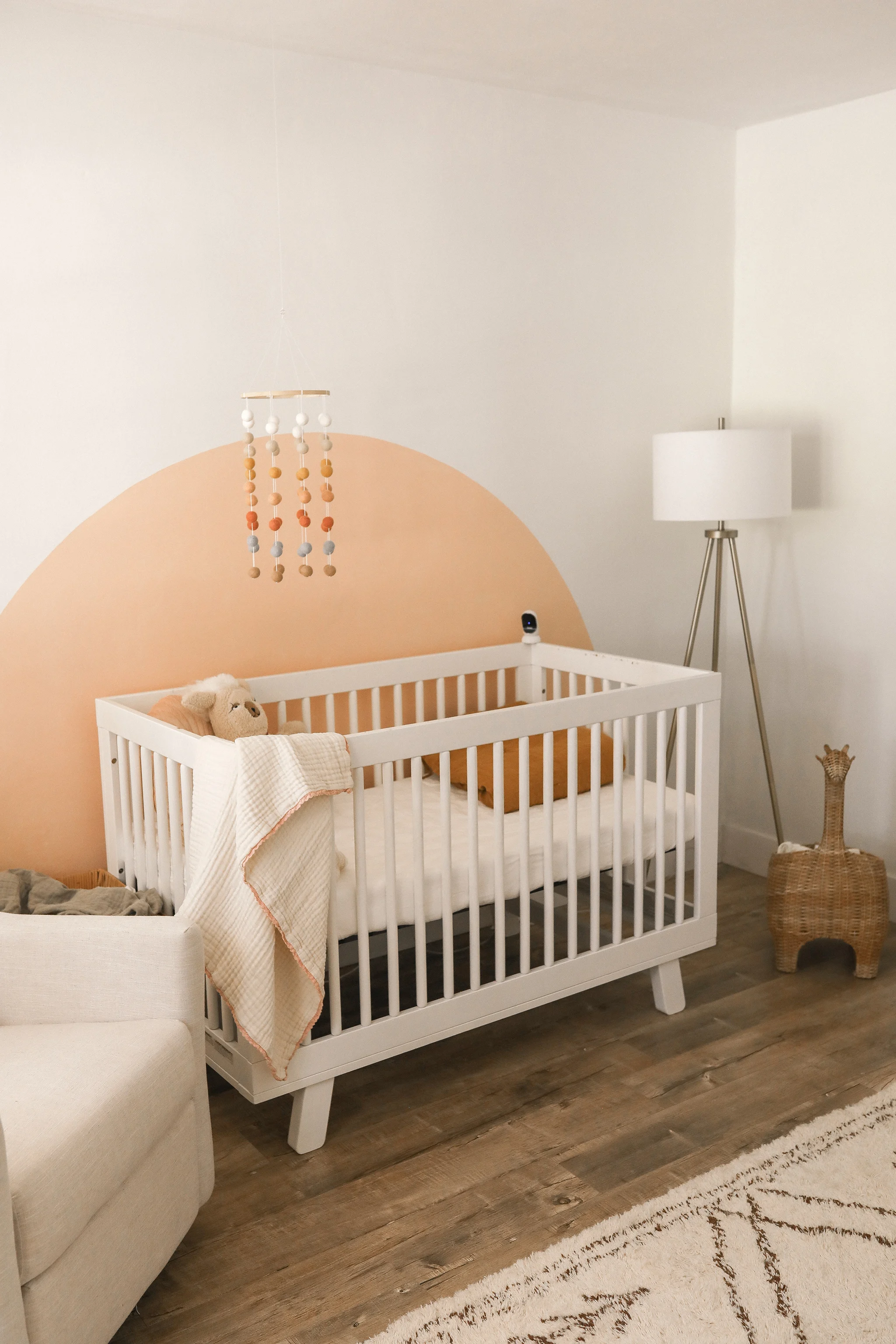 Peach Nursery with Painted Arch behind the Crib designed by Tayler Golden
