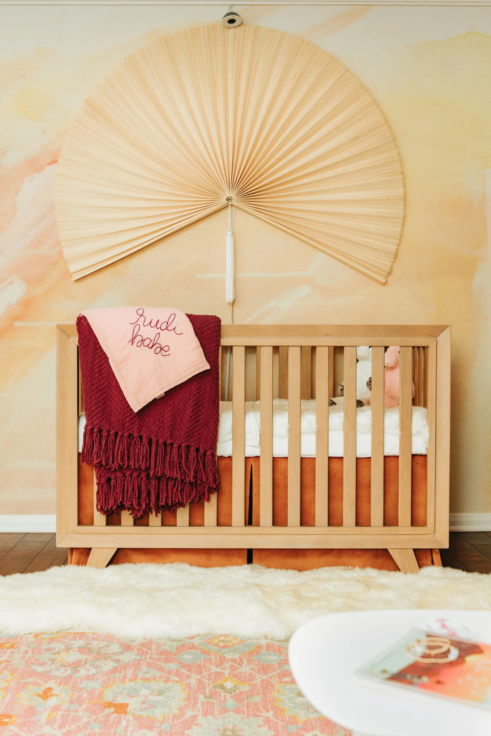 Fan Over Natural Wooster Crib with Abstract Sunrise Wallpaper